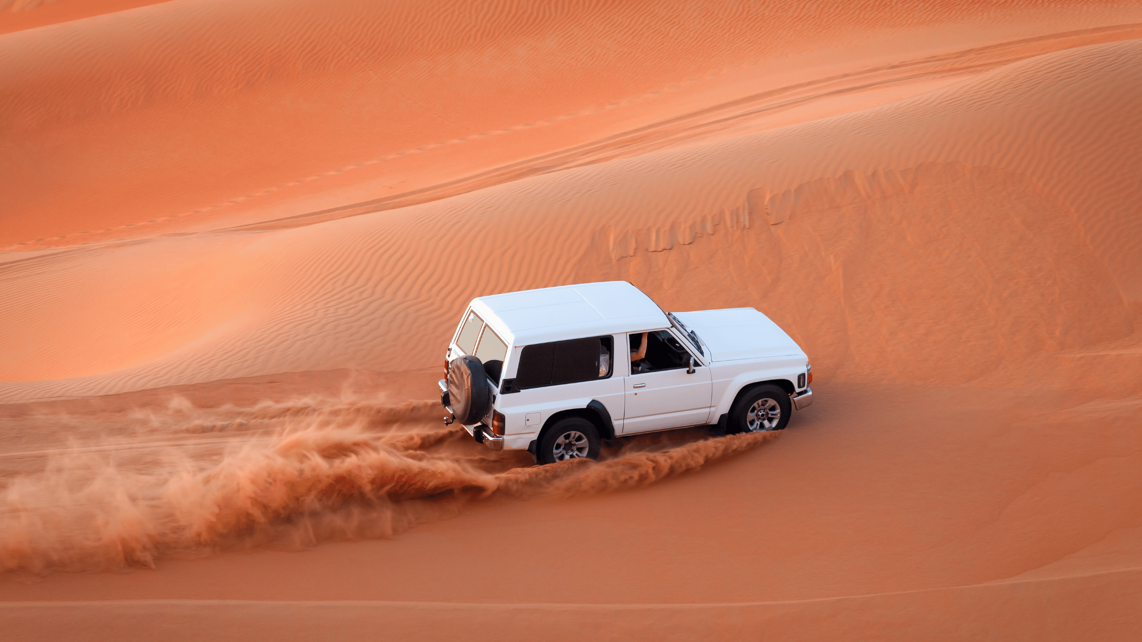 A 4x4 vehicle racing across the golden sands of Dubai’s Lahbab Desert.