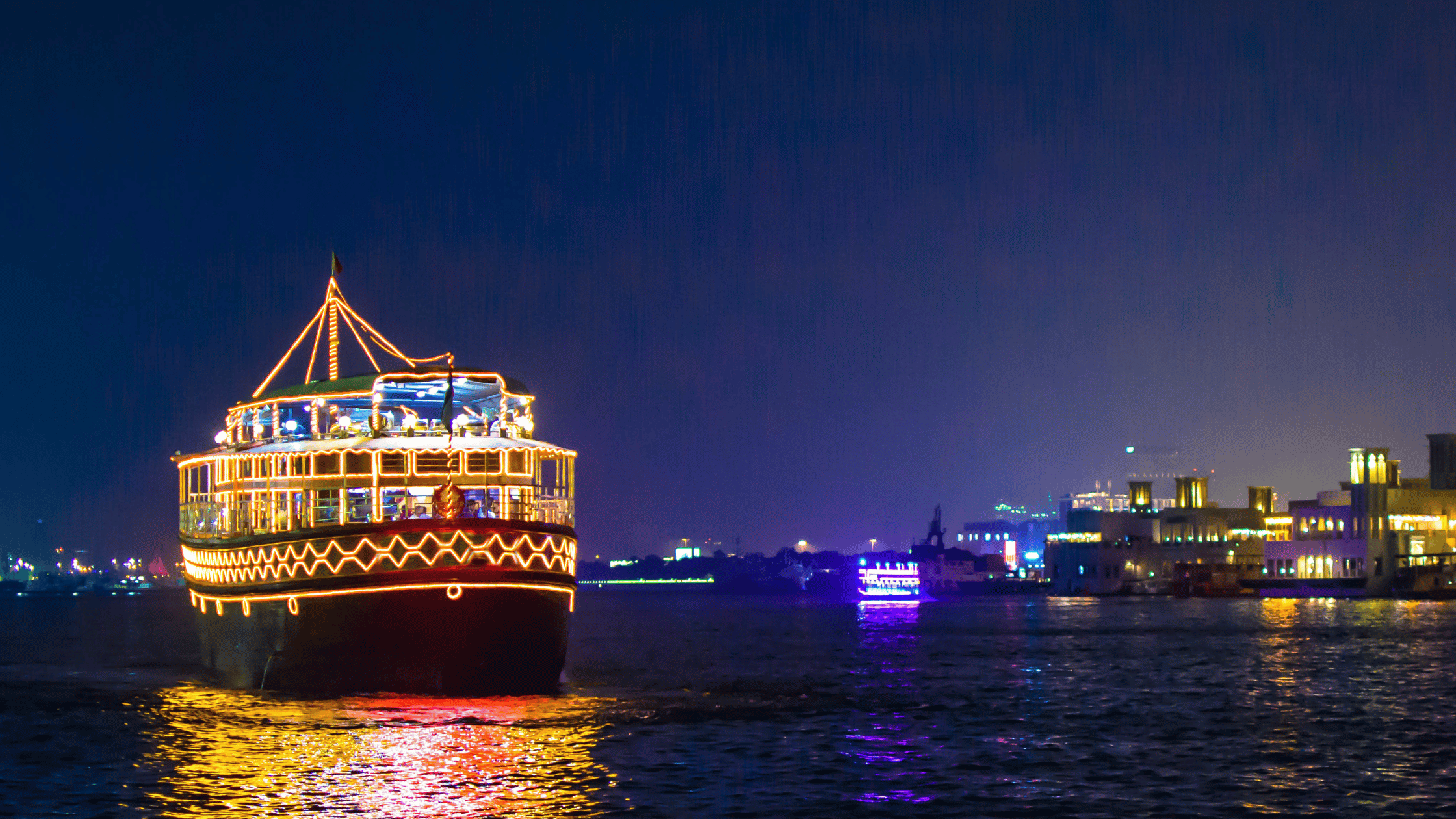 A traditional Dhow Cruise with Dubai Marina skyline illuminated at night.